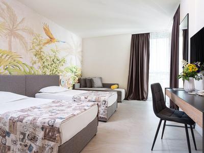 Hell eingerichtetes Hotelzimmer mit zwei Einzelbetten, Sitzbereich und Schreibtisch.