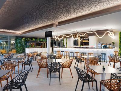 Modernes Hotelrestaurant mit luftiger Atmosphäre und stilvollen Möbeln in Schwarz und Braun.