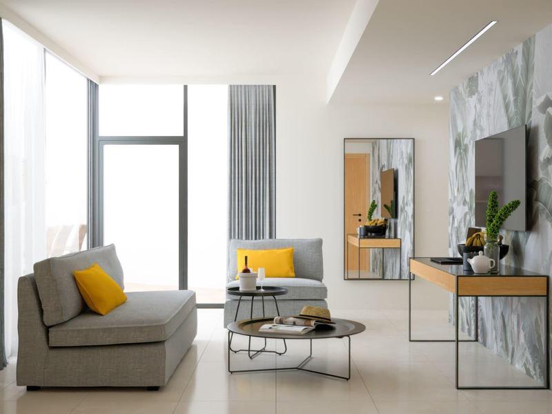 Modernes Wohnzimmer mit grauem Sofa, gelben Kissen, Couchtisch und großem Fenster.