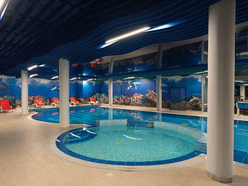 Rundes Hallenbad mit blauer Wandmalerei und Säulen in einem Hotel.