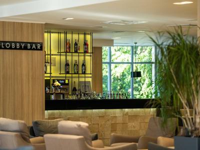 Moderner Lobbybereich mit Bar, bequemen Sesseln und grünen Pflanzen in einem Hotel.