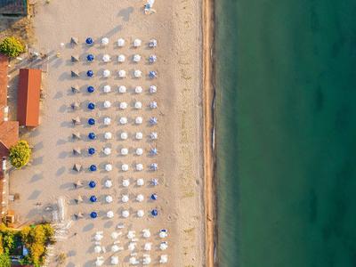 Luchtfoto van een strandhotel met parasols, zandstrand en helder zee.