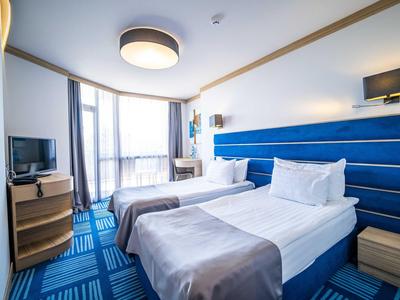 Lichte hotelkamer met twee eenpersoonsbedden, blauwtinten en modern design.