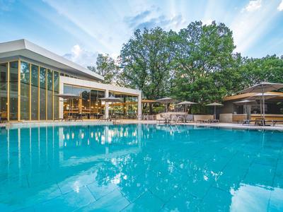 Moderner Hotelpool mit Sonnenterrasse und Pavillon unter blauem Himmel und Bäumen