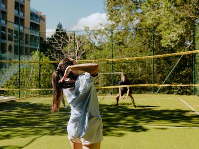 Person spielt Volleyball auf einem grünen Rasenplatz bei sonnigem Wetter.