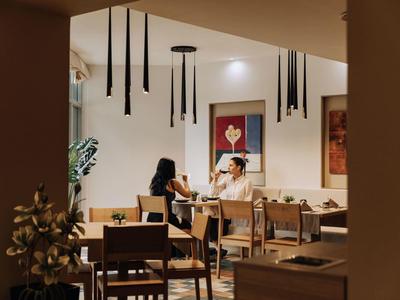 Gasten zitten in een gezellig restaurant met moderne kunst en hanglampen.