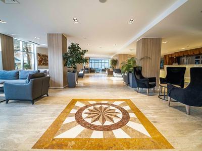 Moderne hotel lounge met zithoeken en decoratief vloerpatroon.