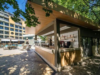 Moderner Kiosk mit schattigem Sitzbereich in einem sonnigen Hotelhof