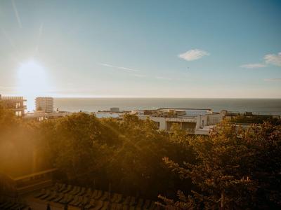 Sonnenuntergang über einer Küstenstadt mit Meer und Gebäuden im Vordergrund.