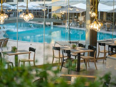 Moderner Innenbereich eines Restaurants mit Blick auf einen beleuchteten Außenpool bei Nacht.