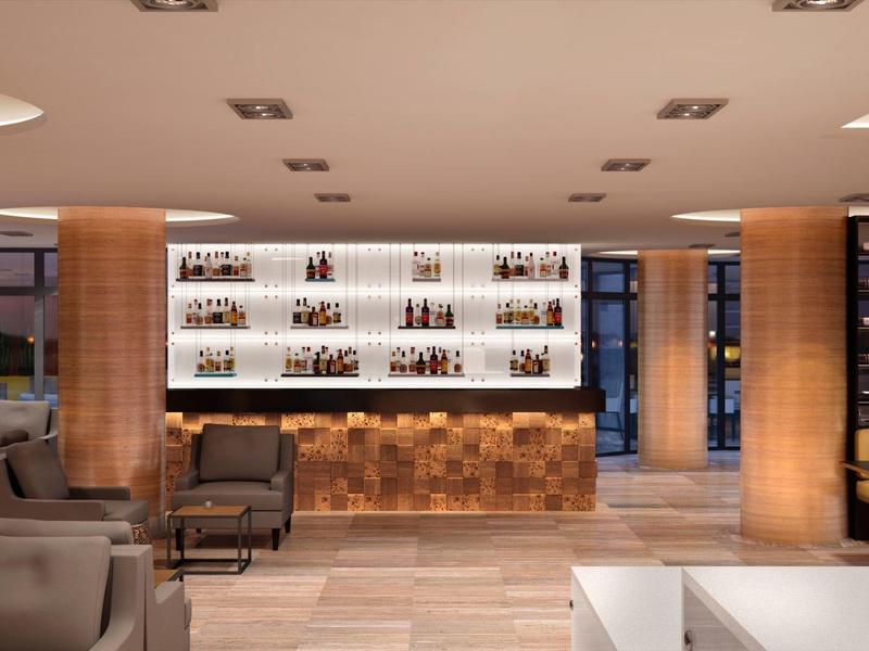 Moderne hotelbar met verlichte planken, gezellige zitplaatsen en licht houtontwerp.