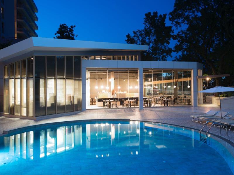 Modern gebouw met grote ramen naast verlicht zwembad 's nachts