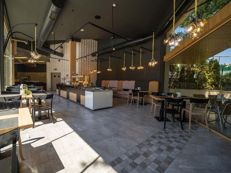 Modern, gezellig café met grote ramen en diverse zitplaatsen.