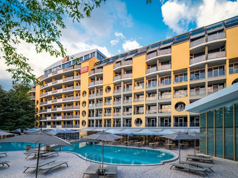 Modern hotelcomplex met zwembad en parasols onder bewolkte lucht