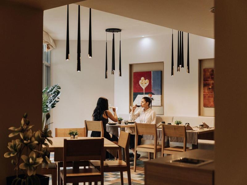 Gasten zitten in een gezellig restaurant met moderne kunst en hanglampen.