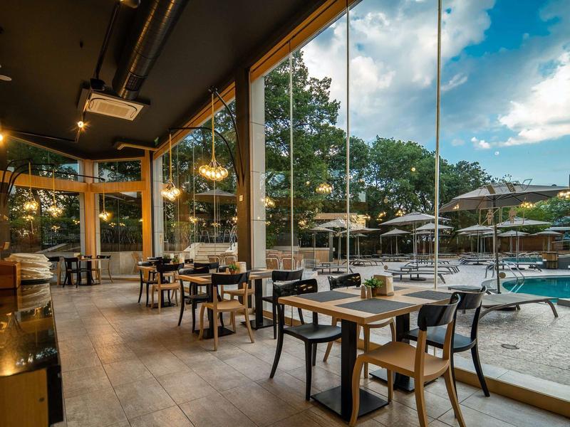 Moderne eetruimte met glazen wanden en uitzicht op een zwembad en buitenruimtes.