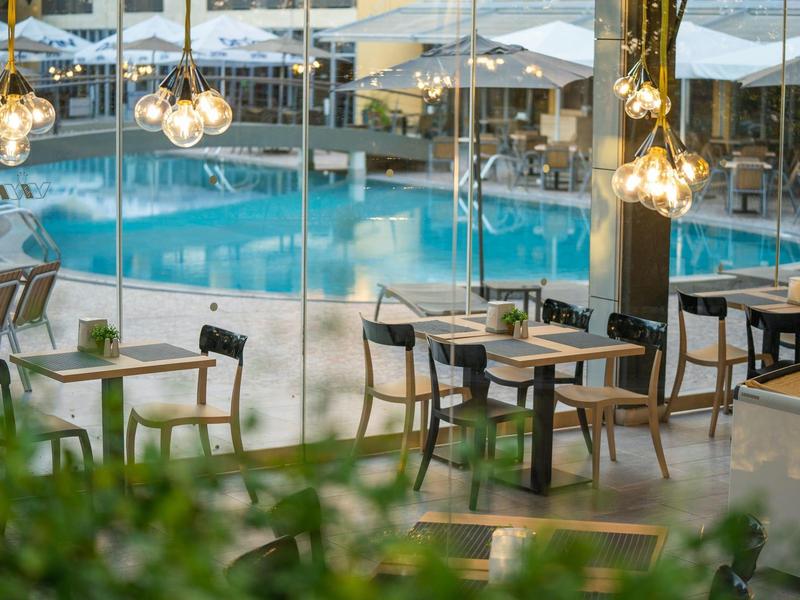 Overdekte restaurantgedeelte met uitzicht op een zwembad en zitplaatsen buiten.