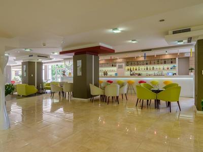 Área de salón de hotel bien iluminada con sillas de colores y recepción moderna.