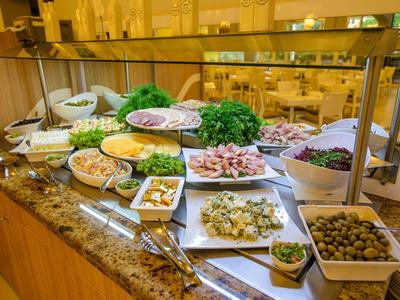Buffet con varias ensaladas, aceitunas, hierbas y aderezos sobre un mostrador de mármol.