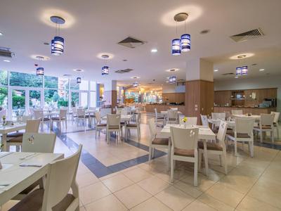 Restaurante moderno y luminoso del hotel con sillas blancas y grandes ventanas que proporcionan luz natural.