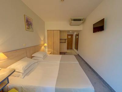 Habitación de hotel luminosa con dos camas, mesitas y decoración moderna en la pared.