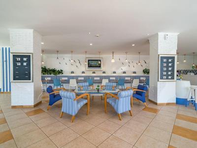 Área de restaurante de hotel con sillas azules y mesas de madera, decoración moderna y luz natural