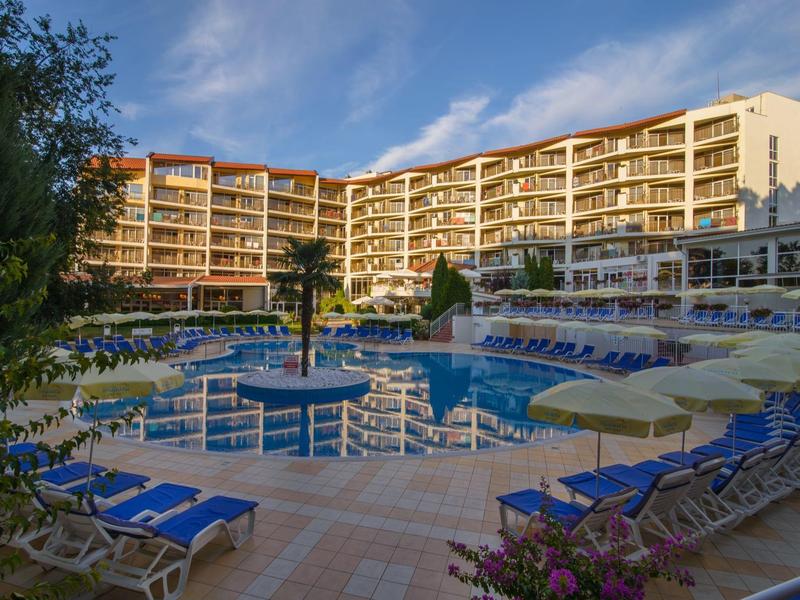Gran hotel con edificio curvado, piscina y muchas tumbonas bajo el sol.