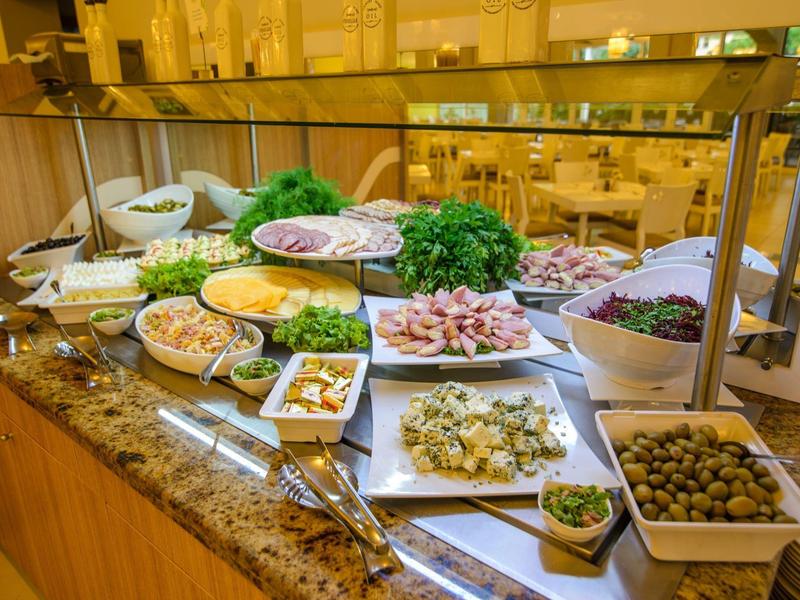 Buffet con varias ensaladas, aceitunas, hierbas y aderezos sobre un mostrador de mármol.