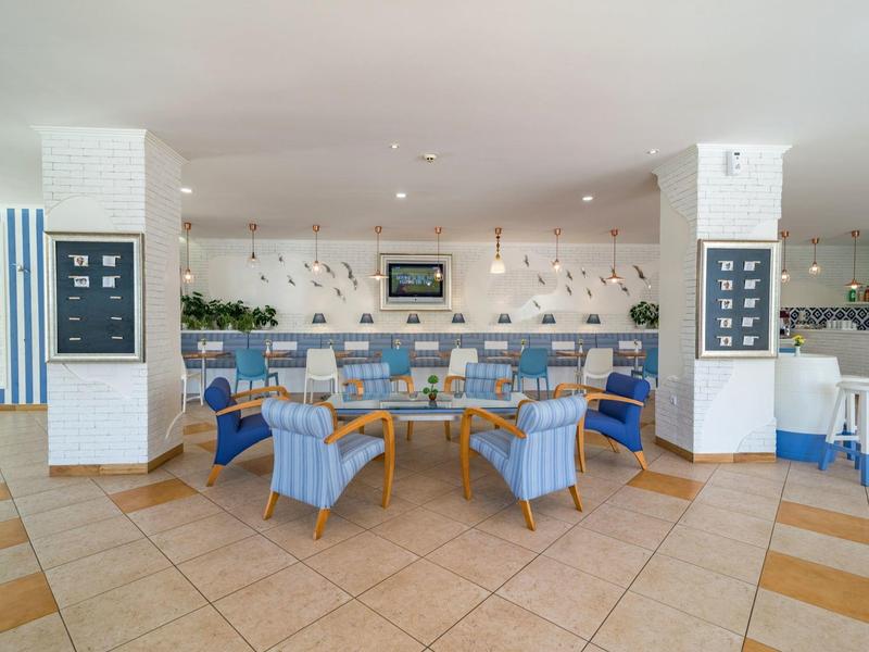 Área de restaurante de hotel con sillas azules y mesas de madera, decoración moderna y luz natural