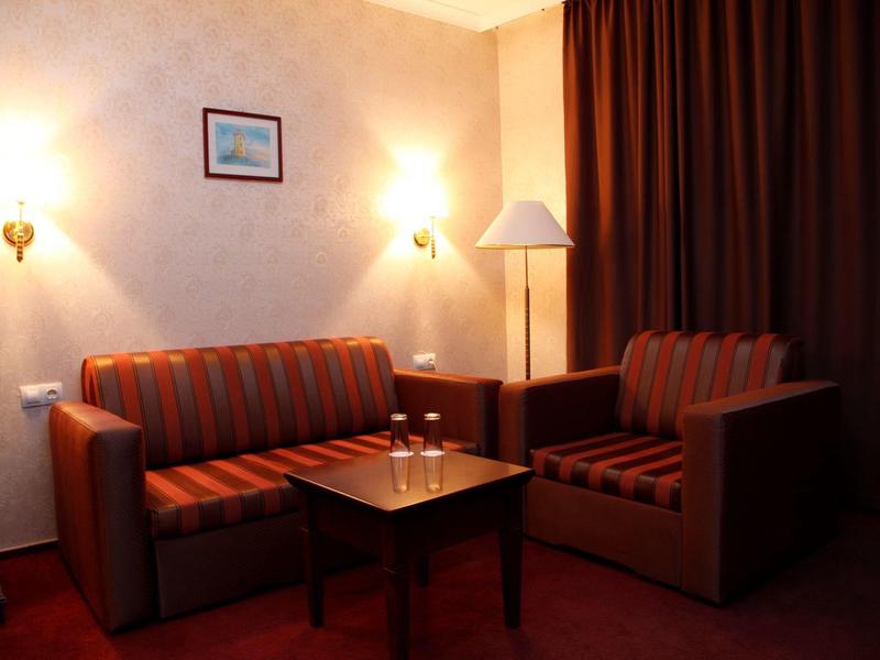 Kleiner Wohnbereich mit zwei braunen Sofas, kleinem Holztisch und warmem, gedämpftem Licht.