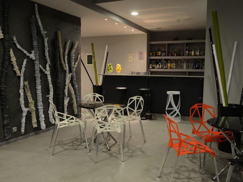 Moderner Raum mit ungewöhnlichen Stühlen, Bar im Hintergrund und dekorativen weißen Baumstämmen an der Wand.