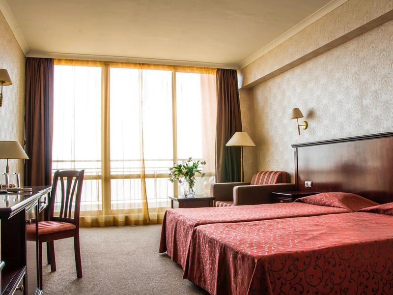 Gemütliches Hotelzimmer mit zwei Einzelbetten, großem Fenster und klassischer Einrichtung.