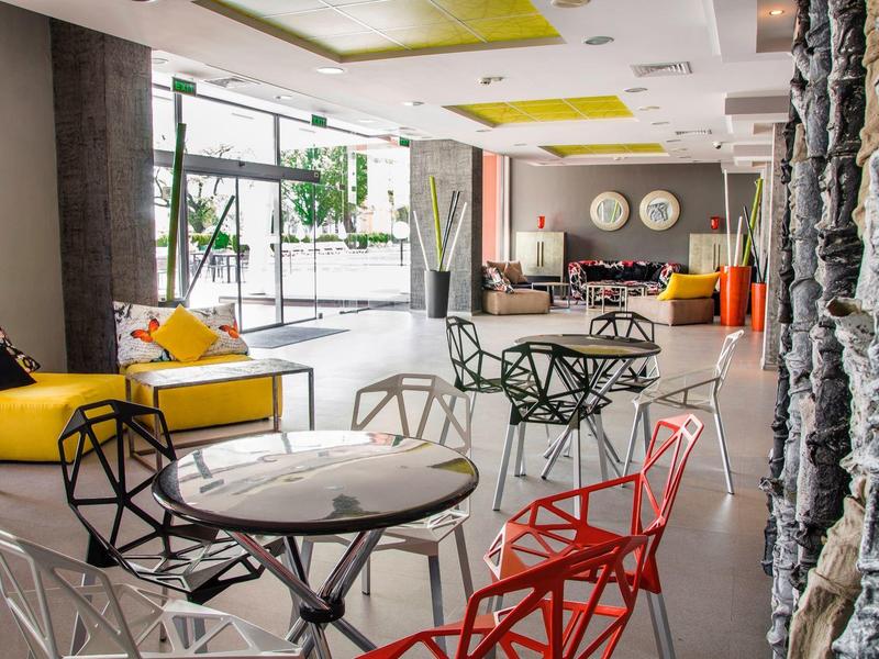 Moderner Innenraum mit bunten Stühlen, großen Fenstern und natürlichem Tageslicht.