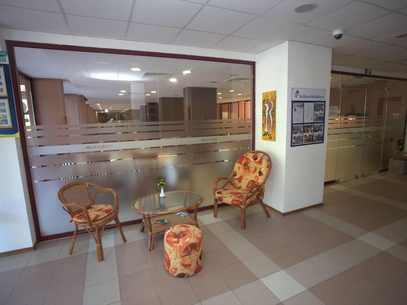 Zitgedeelte met twee stoelen, een kruk en een kleine tafel voor een glazen wand in een hotel.