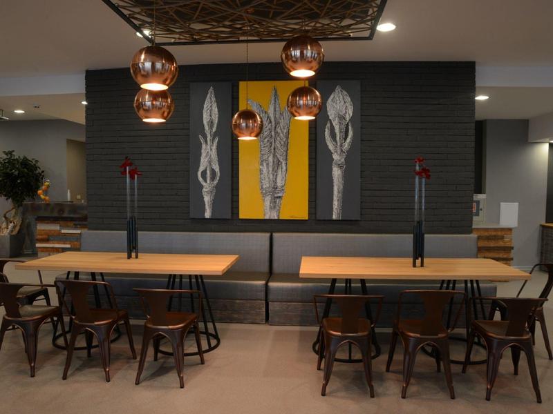 Moderne eetruimte met houten tafels, stoelen en decoratieve wandkunst in een hotel.