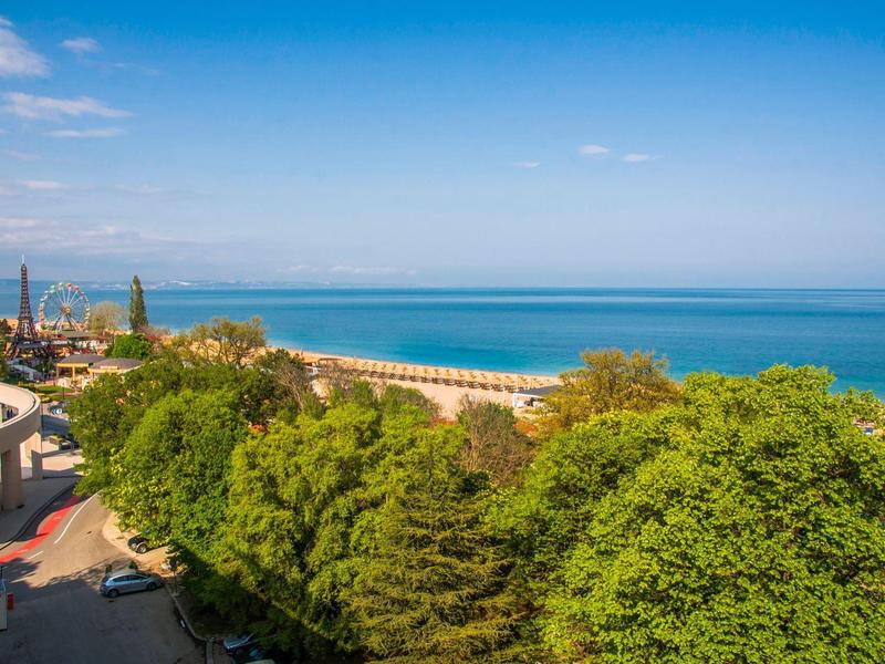 Uitzicht op zee met groene bomen en blauwe lucht, ideaal voor vakantie en ontspanning.