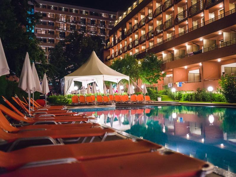 Verlicht hotelzwembad met ligstoelen en parasols in de nacht