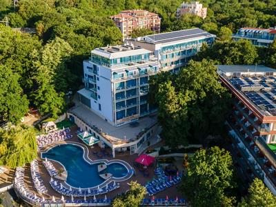 Hotelkomplex mit Pool, umgeben von dichter grüner Vegetation und mehreren Gebäuden.