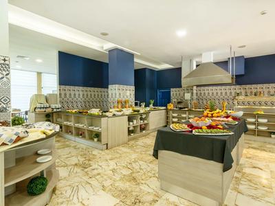 Heller Frühstücksraum mit Marmorboden, blauen Wänden, Buffets und einer Auswahl an Obst und Backwaren.