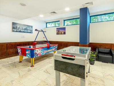 Freizeitraum mit Airhockey- und Tischfußballtisch, Sitzbereich und großen Fenstern.