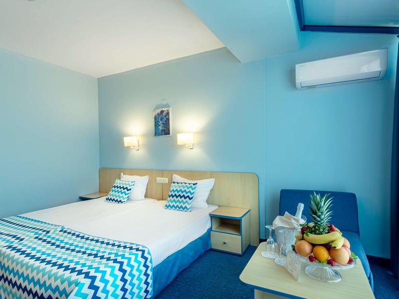 Modernes Schlafzimmer mit großem Bett, blauem Wandanstrich, Nachttischen und Obstkorb auf Tisch.