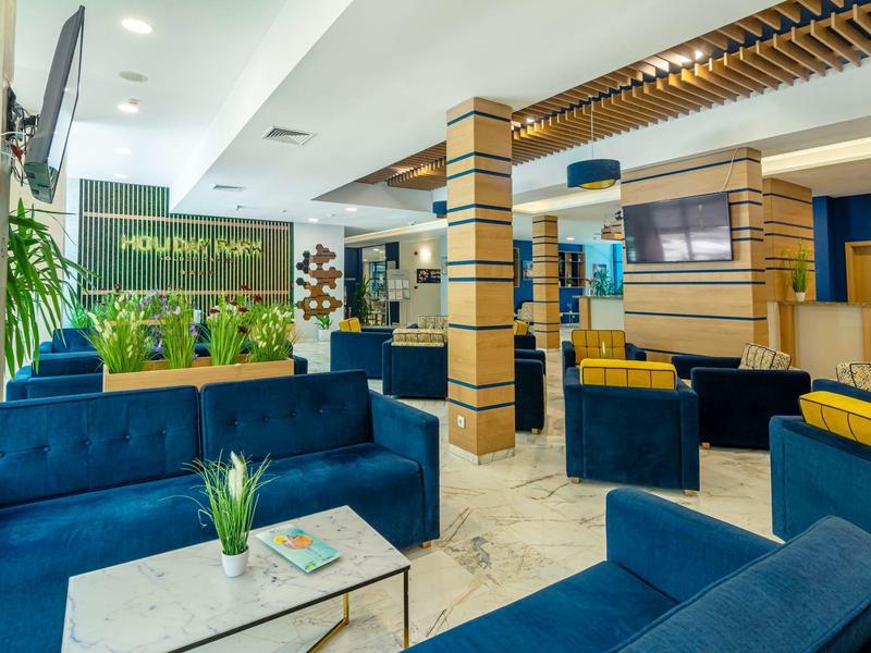 Modern eingerichteter Wartebereich mit blauen Sofas, Pflanzen und hellen Marmorböden.