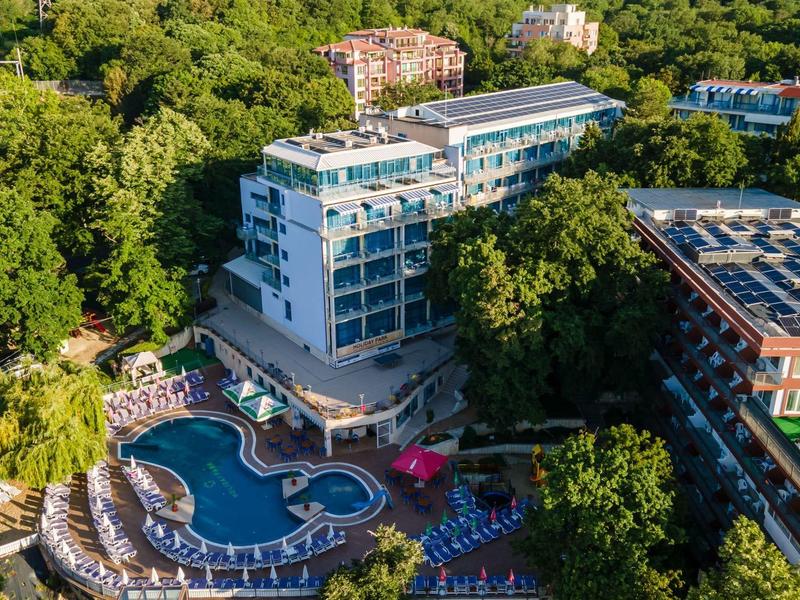 Hotelkomplex mit Pool, umgeben von dichter grüner Vegetation und mehreren Gebäuden.