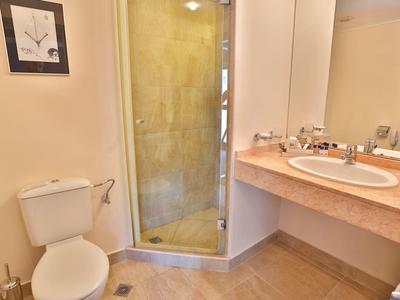 Baño pequeño con inodoro, ducha con puerta de vidrio y lavabo con espejo.