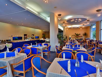 Comedor bien iluminado con mesas vestidas de azul y muebles de madera en un hotel.