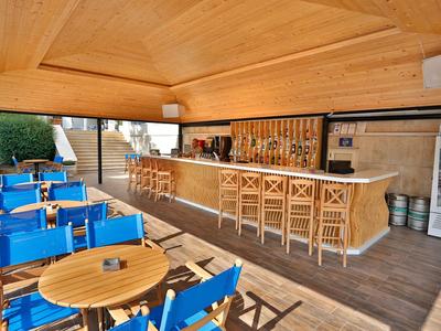 Moderno área de bar al aire libre con techo de madera, taburetes y sillas azules