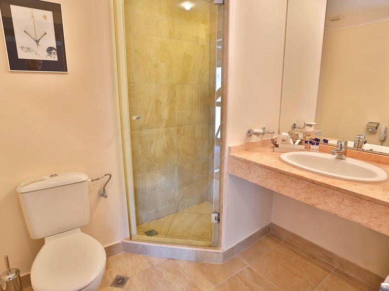 Baño pequeño con inodoro, ducha con puerta de vidrio y lavabo con espejo.