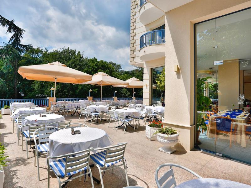 Terraza del hotel con mesas, sillas y sombrillas bajo el sol.