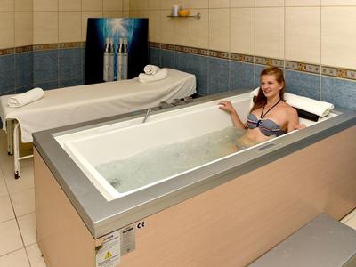 Donna si rilassa in una vasca moderna in una stanza piastrellata con lettini da massaggio.