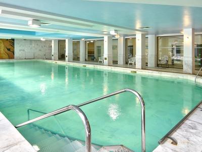 Piscina coperta con ampio bacino, scala e atmosfera rilassata in un hotel moderno.